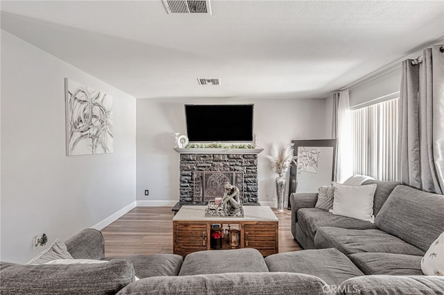 living area with visible vents, baseboards, wood finished floors, and a fireplace