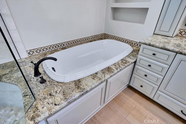 full bath featuring a garden tub and wood finished floors