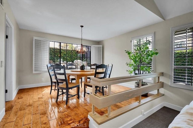 dining area with baseboards, light wood-type flooring, and a chandelier