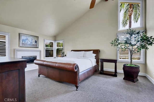 bedroom with high vaulted ceiling, baseboards, a glass covered fireplace, and carpet