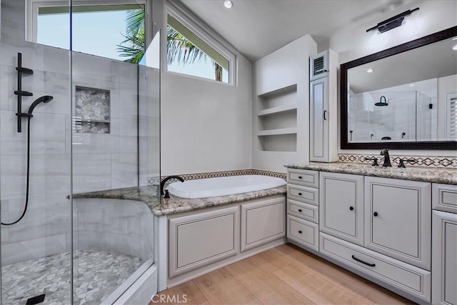 bathroom featuring a shower stall, a garden tub, vanity, wood finished floors, and lofted ceiling