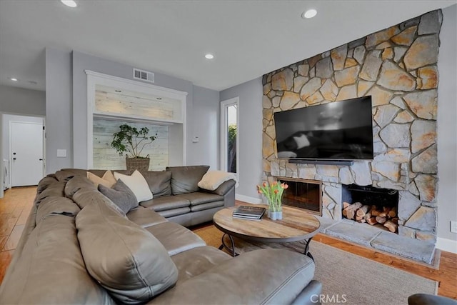 living room featuring visible vents, baseboards, a fireplace, recessed lighting, and wood finished floors