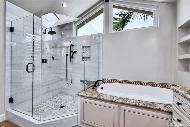 bathroom with a shower stall, a garden tub, vanity, and plenty of natural light