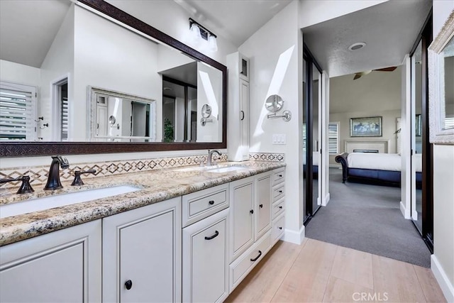 ensuite bathroom with double vanity, ensuite bathroom, a sink, and wood finished floors