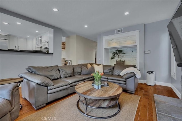 living room featuring hardwood / wood-style floors, baseboards, visible vents, and recessed lighting