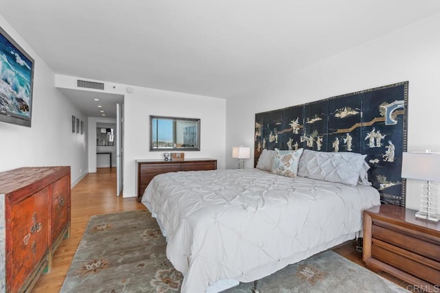 bedroom with baseboards, wood finished floors, and visible vents