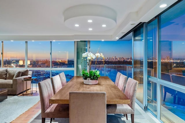 dining space with wood finished floors, a view of city, a wall of windows, a notable chandelier, and recessed lighting