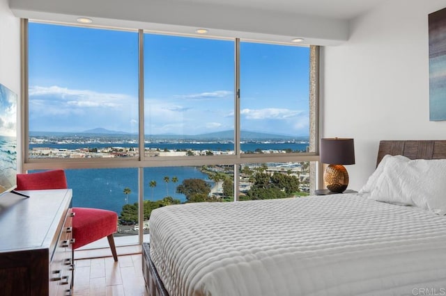 bedroom featuring expansive windows, a water and mountain view, and recessed lighting