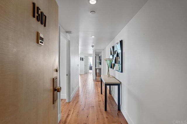 hall featuring light wood-style flooring and baseboards