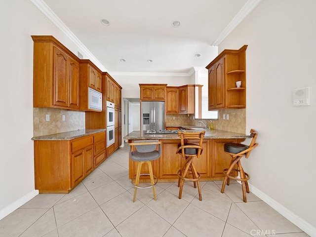 8309 Hillside Rd, Alta Loma, CA 91701 - kitchen featuring white appliances, a peninsula, decorative backsplash, brown cabinetry, and ornamental molding