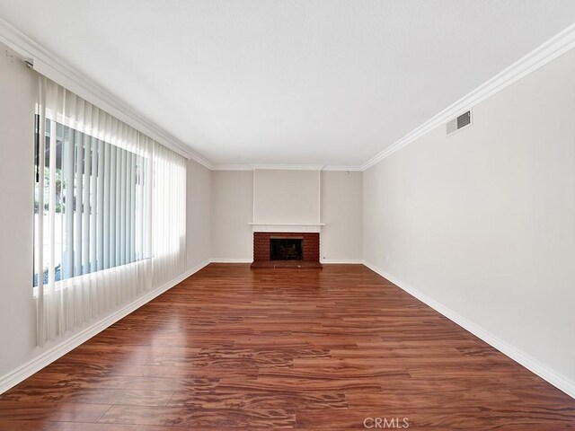 8309 Hillside Rd, Alta Loma, CA 91701 - unfurnished living room featuring dark wood-type flooring, baseboards, crown molding, and a brick fireplace