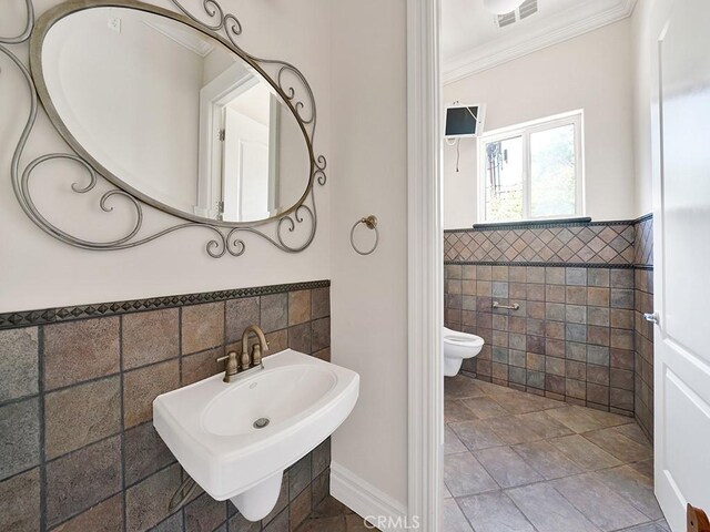 8309 Hillside Rd, Alta Loma, CA 91701 - bathroom with tile walls, a wainscoted wall, ornamental molding, a bidet, and a sink
