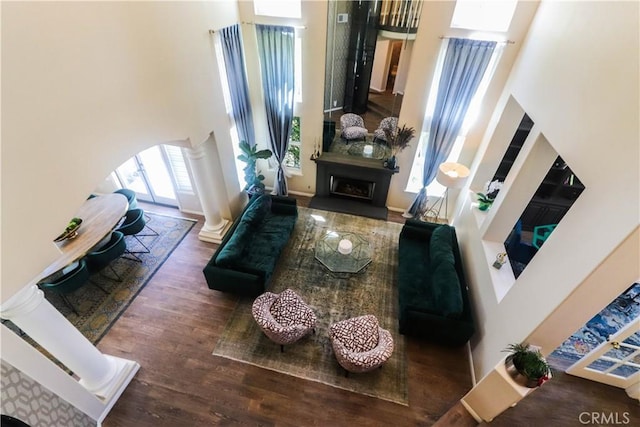 26962 Willow Tree Ln, Laguna Hills, CA 92653 - living area with wood finished floors, a fireplace with raised hearth, arched walkways, a high ceiling, and decorative columns