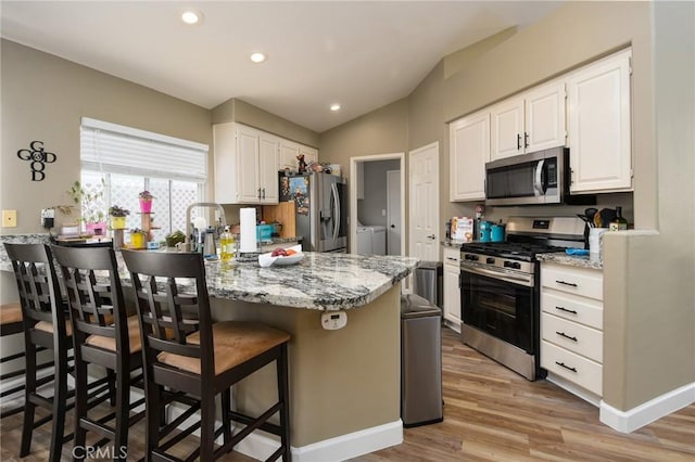 23898 Via Pamilla, Murrieta, CA 92562 - kitchen featuring stainless steel appliances, washer and clothes dryer, a peninsula, white cabinetry, and lofted ceiling