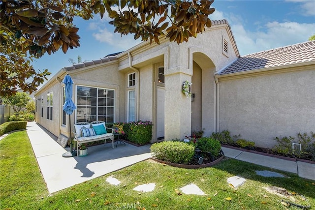 23898 Via Pamilla, Murrieta, CA 92562 - view of exterior entry featuring stucco siding, a yard, a tile roof, and a patio area