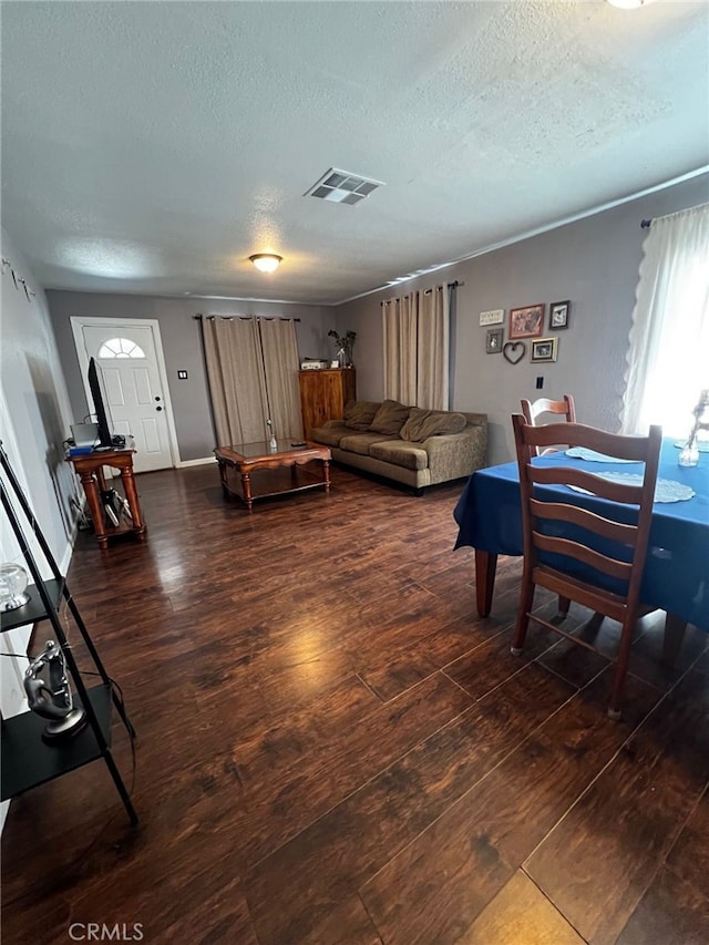 living area featuring a textured ceiling, baseboards, dark wood-style floors, and visible vents