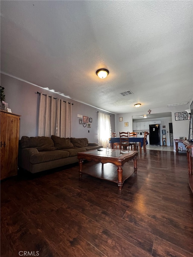 living room with visible vents, a textured ceiling, and wood finished floors