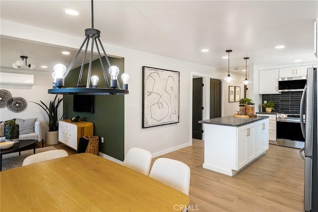 kitchen featuring light wood-style flooring, white cabinets, appliances with stainless steel finishes, and dark countertops