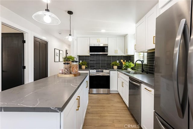 kitchen with appliances with stainless steel finishes, a center island, white cabinetry, decorative backsplash, and a sink