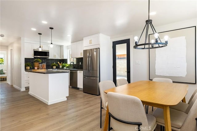 dining area with a chandelier, recessed lighting, baseboards, and light wood-style flooring