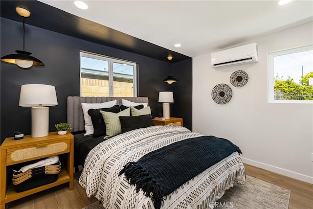 bedroom with a wall mounted air conditioner, recessed lighting, baseboards, and wood finished floors