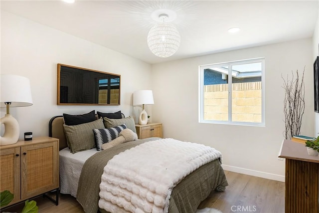 bedroom with baseboards, light wood finished floors, an inviting chandelier, and recessed lighting