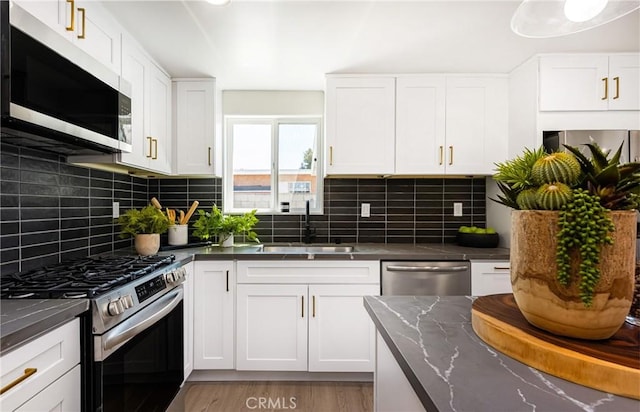 kitchen with decorative backsplash, white cabinetry, a sink, and appliances with stainless steel finishes