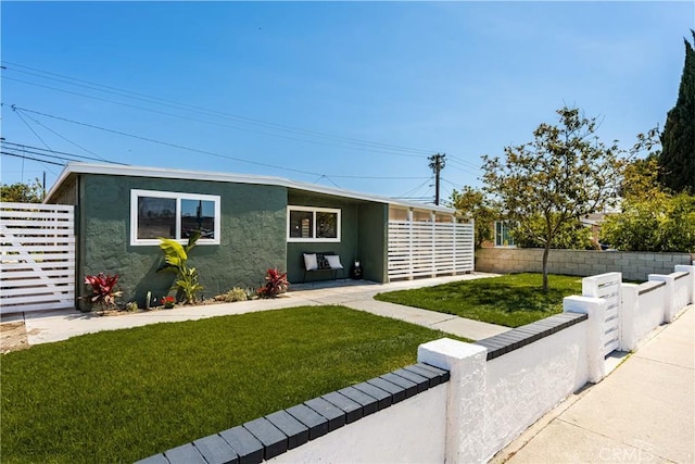 view of front facade with a front yard, stucco siding, and fence
