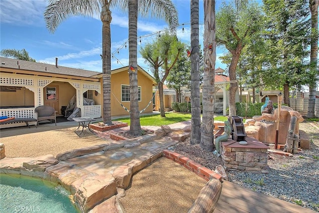rear view of property featuring a patio area, fence, and stucco siding