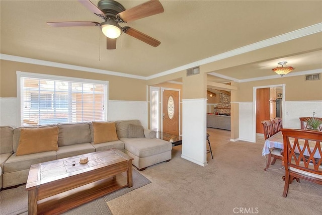 living area featuring crown molding, light colored carpet, a ceiling fan, and visible vents
