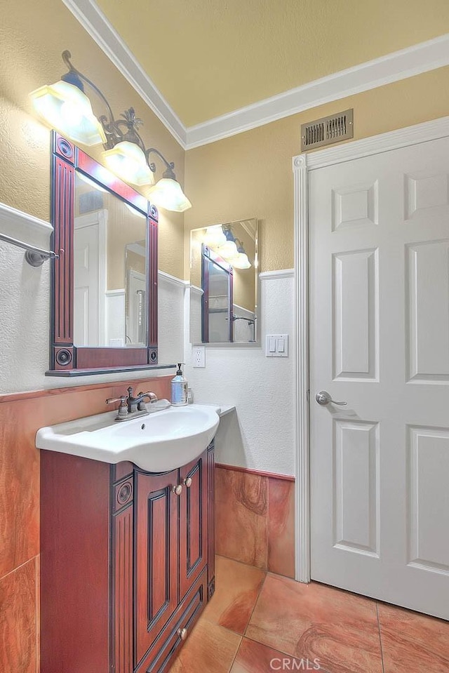 bathroom with visible vents, ornamental molding, a textured wall, vanity, and tile patterned flooring