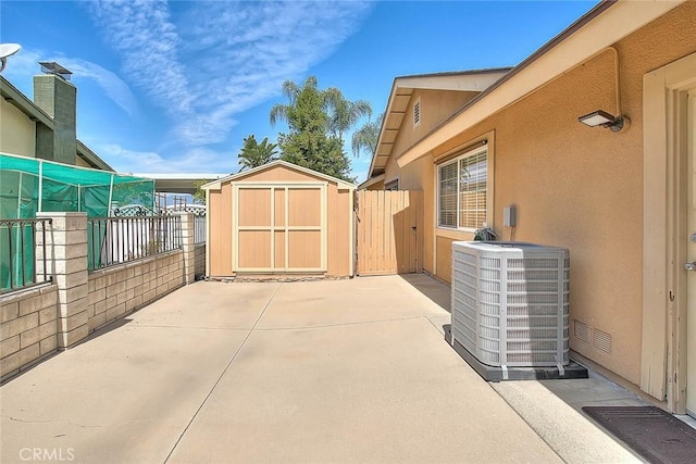 view of patio / terrace featuring central AC unit, fence, an outbuilding, and a storage unit