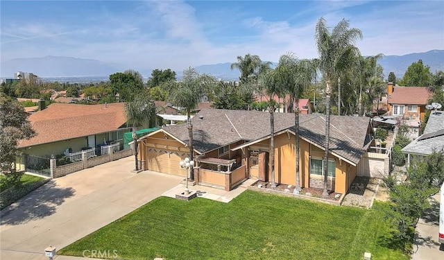 view of front of property with a front yard, a mountain view, an attached garage, fence, and driveway