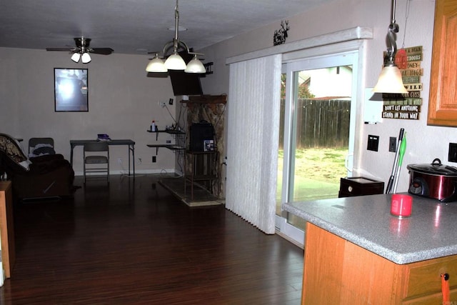 kitchen featuring a ceiling fan, brown cabinets, hanging light fixtures, and dark wood-type flooring