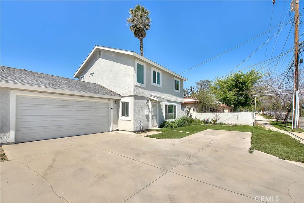 417 N Grove Ave, Ontario, CA 91764 - traditional home with an attached garage, fence, stucco siding, a front lawn, and driveway