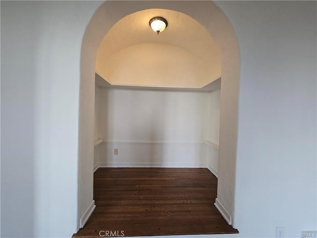 hallway featuring wood finished floors and arched walkways
