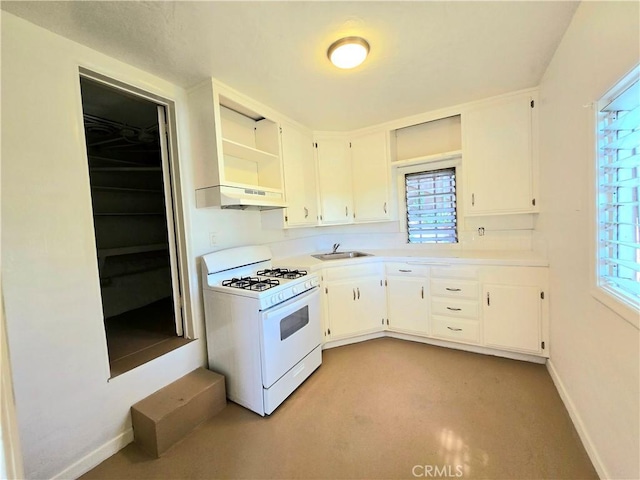kitchen featuring white cabinets, under cabinet range hood, a sink, and white gas range oven