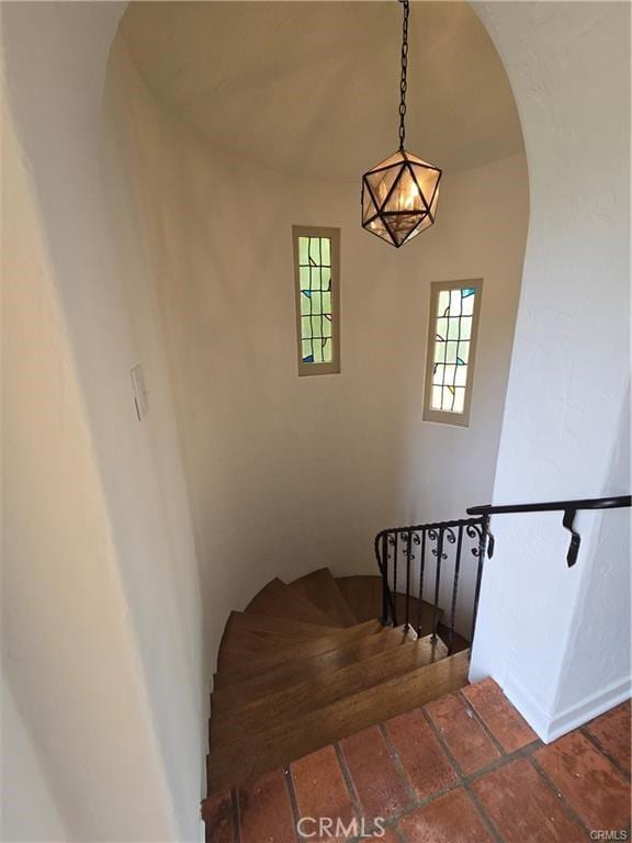 staircase with arched walkways and baseboards