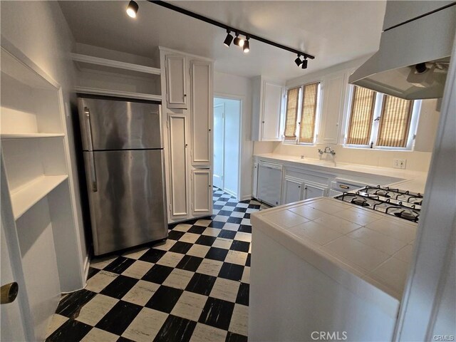 kitchen with freestanding refrigerator, range hood, dark floors, dishwasher, and tile countertops