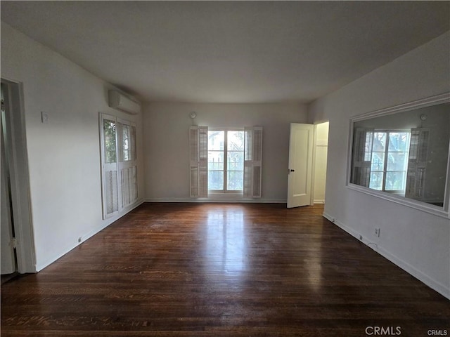 interior space featuring baseboards, a wall unit AC, and dark wood finished floors