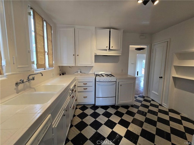 kitchen with dark floors, white range with gas cooktop, white cabinetry, and a sink