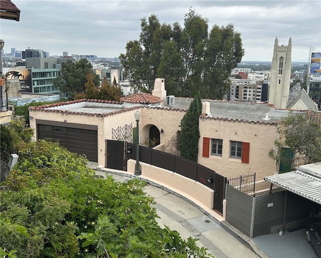 view of front of house featuring a tile roof, a garage, fence private yard, a view of city, and stucco siding