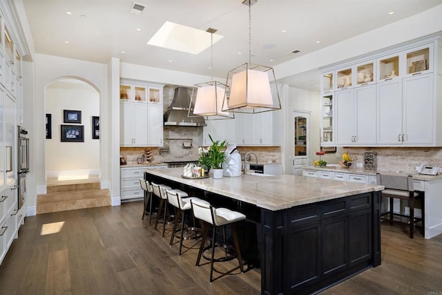 18320 Colina Fuerte, Rancho Santa Fe, CA 92067 - kitchen featuring wall chimney exhaust hood, a skylight, white cabinetry, a large island, and dark wood-type flooring