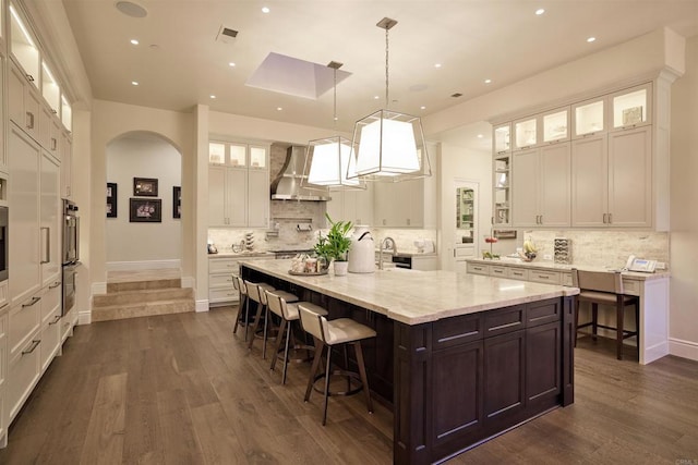 18320 Colina Fuerte, Rancho Santa Fe, CA 92067 - kitchen with wall chimney exhaust hood, white cabinetry, a large island with sink, dark brown cabinetry, and a kitchen breakfast bar