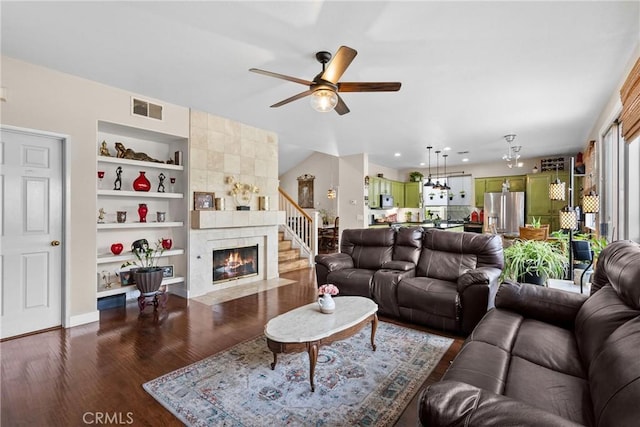 13126 Glandt Ct, Corona, CA 92883 - living room featuring visible vents, built in shelves, a tiled fireplace, a ceiling fan, and dark wood-type flooring