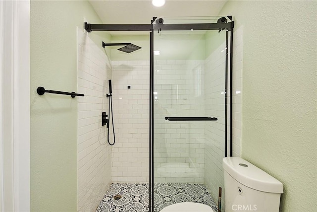 bathroom featuring a shower stall, toilet, and a textured wall