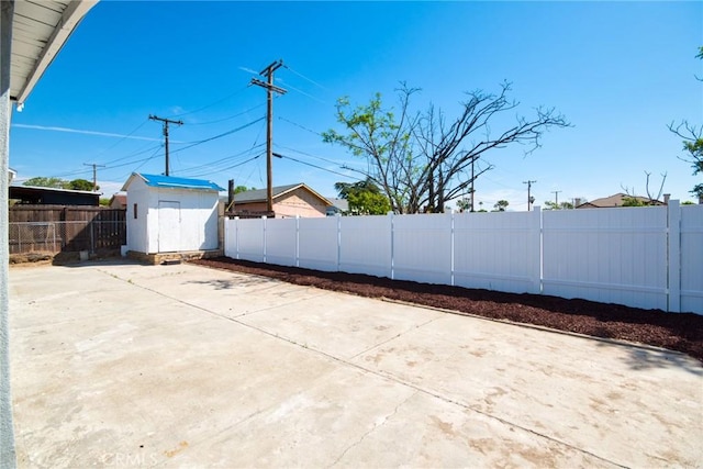 view of patio / terrace featuring a fenced backyard, an outdoor structure, and a shed