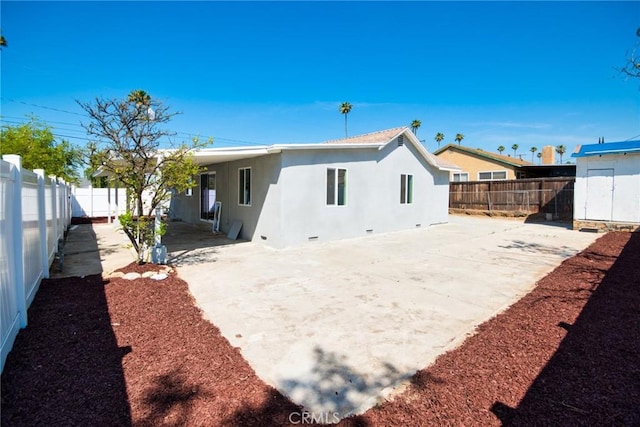 rear view of house with a fenced backyard, stucco siding, a patio, and concrete driveway