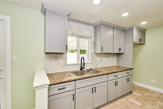 kitchen with a sink, light wood-style floors, recessed lighting, gray cabinetry, and backsplash