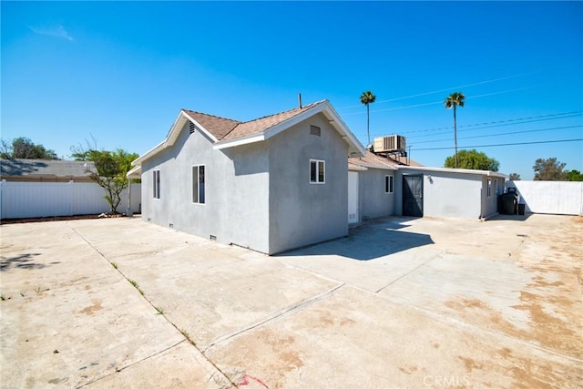 exterior space with concrete driveway, central air condition unit, stucco siding, a patio area, and fence